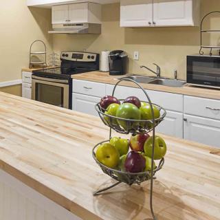 A modern kitchen with a wooden countertop and a fruit basket filled with apples.