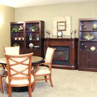 A cozy living room setup featuring a dining table, chairs, and elegant bookshelves surrounding a fireplace.