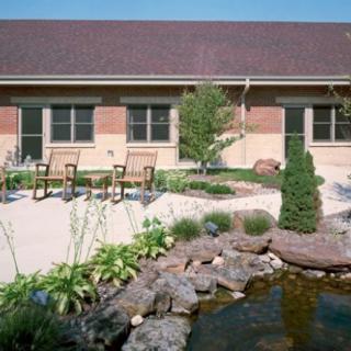 A serene garden patio with a pond and outdoor seating.