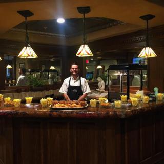 A chef stands behind a buffet counter at a restaurant, showcasing an assortment of dishes.