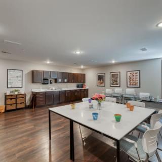 A modern kitchen and dining area with a large table, chairs, and sleek cabinets.