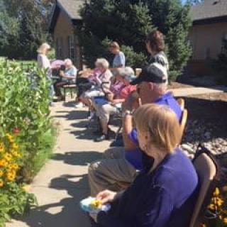 A group of people sitting outdoors in a garden on a sunny day.