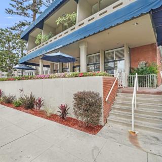 A building entrance featuring stairs, a blue awning, and landscaped plants.