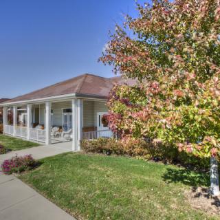 A house with a front porch surrounded by autumn foliage.