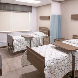 A clean and organized hospital room with multiple beds and privacy curtains.