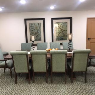 A stylish dining area featuring a long table with green upholstered chairs and decorative artwork on the walls.