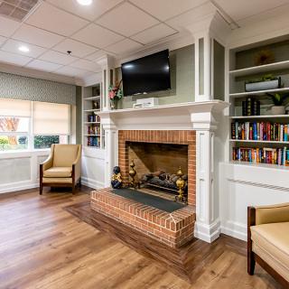 A cozy living room with a brick fireplace, bookshelves, and comfortable armchairs.