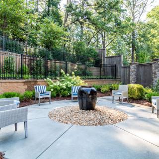 A serene outdoor patio area featuring modern furniture and lush greenery.