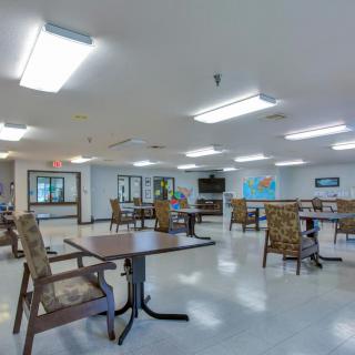 A spacious dining room with tables, chairs, and a television for communal gatherings.