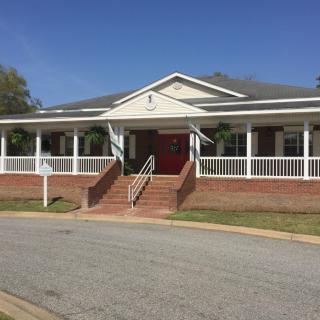 A residential building with a large front porch and red door.