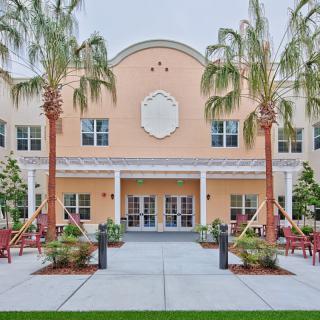 A building entrance framed by palm trees and well-maintained landscaping.