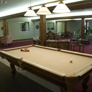 A spacious game room featuring a pool table with overhead lighting.