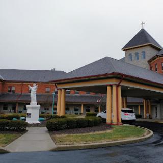 A view of a church building featuring a statue and beautifully landscaped surroundings.