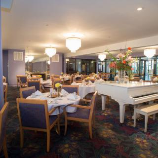 Elegant dining area with a grand piano and beautifully set tables.