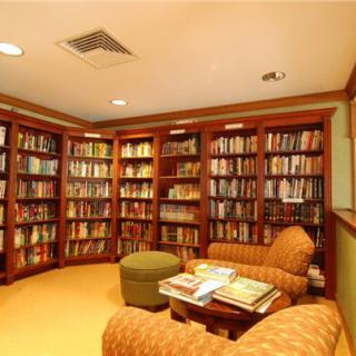 A cozy library with wooden bookshelves and comfortable seating.