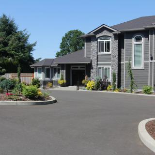 A large residential home with a landscaped driveway under a clear blue sky.