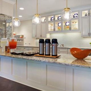 A modern kitchen with a granite countertop featuring beverage dispensers and stylish lighting.