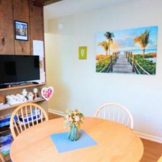 A cozy dining area featuring a wooden table with a vase of flowers, a television, and artwork on the wall.
