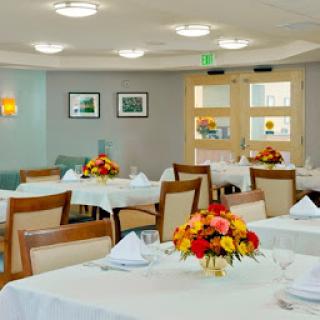 A beautifully arranged dining room with elegantly set tables and vibrant floral centerpieces.