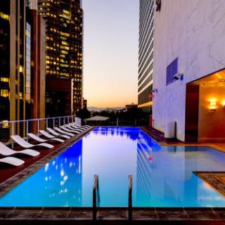 A stunning rooftop pool overlooking a vibrant city skyline at sunset.