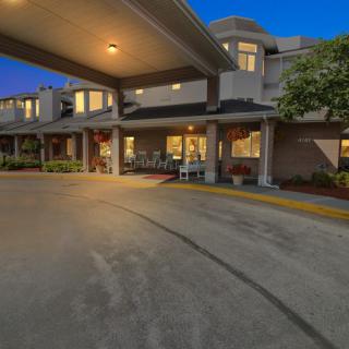 A well-lit building entrance with a covered driveway in the evening.
