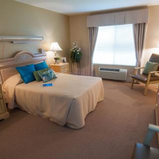 A cozy and well-decorated bedroom with a bed, chair, and lamp.