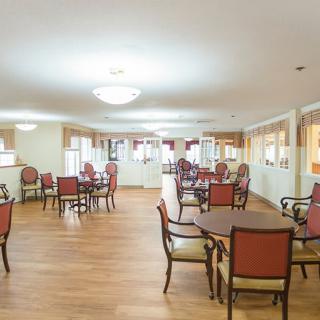 A bright and spacious dining area with wooden floors, furnished with multiple tables and chairs.