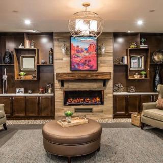 A cozy living room with modern furnishings and a central fireplace.