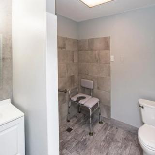 A modern bathroom featuring an accessible shower with a shower chair.