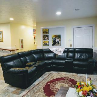 A cozy living room featuring a black leather sectional sofa, colorful rug, and decorative wall art.