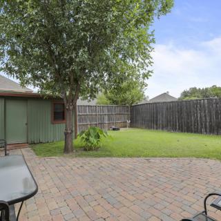 A peaceful backyard with a tree and a patio set on a sunny day.