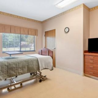 A hospital room with a bed, television, and window.