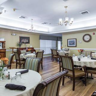 A well-arranged dining room with neatly set tables and elegant chandeliers.
