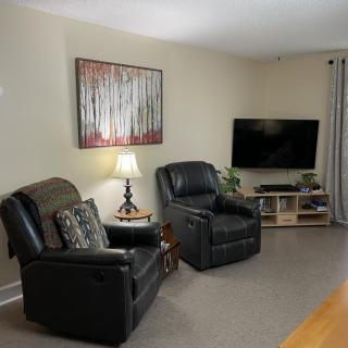 A cozy living room with two recliners facing a television, decorated with artwork and a lamp.