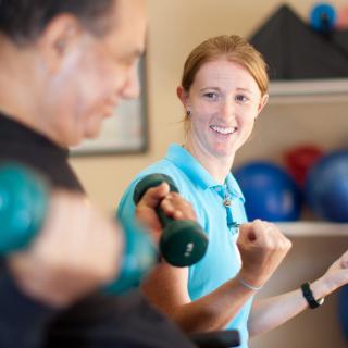 A personal trainer guiding a client during a weightlifting session at the gym.