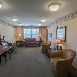 A cozy living room with a sofa, chairs, and a piano.