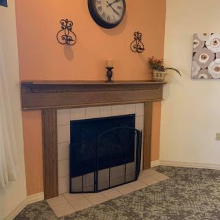 A cozy living room with a fireplace featuring an orange accent wall and decorative elements on the mantel.