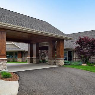 A modern building with a covered entrance and landscaped surroundings.