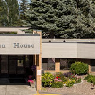 A welcoming entrance to a modern building surrounded by greenery and colorful flowers.
