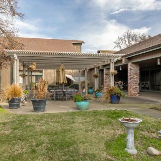 Cozy backyard patio featuring a pergola, outdoor seating, and a well-maintained garden with potted plants.