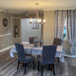 A cozy dining room with a table, four chairs, and a chandelier overhead.