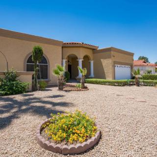 A single-story home with stucco exterior and desert landscaping in the front yard.
