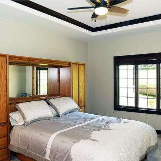 A cozy bedroom with a wooden headboard and ceiling fan.