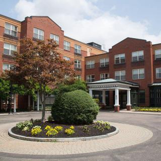 Exterior view of a hotel with landscaped gardens and a roundabout.