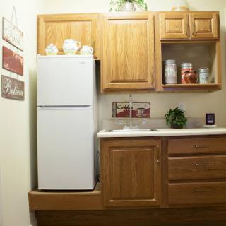 A cozy kitchen corner featuring a refrigerator and wooden cabinets.