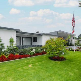 A suburban house with a well-maintained lawn and garden, featuring an American flag on display.