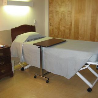 A hospital room featuring an adjustable medical bed with a side table.