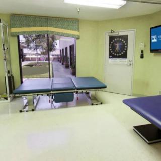 A clean and organized clinic examination room with treatment tables and a view of the outdoors.