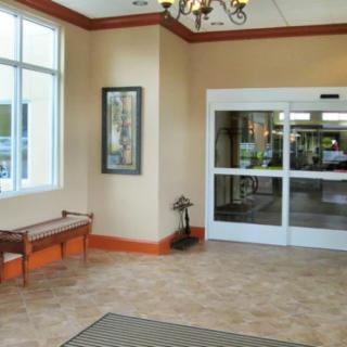 A spacious lobby area with a bench, chandelier, and large sliding glass doors leading outside.