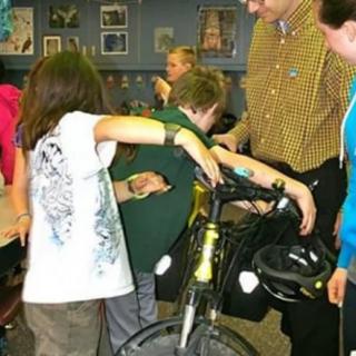 Children interacting with a bicycle in a classroom setting.